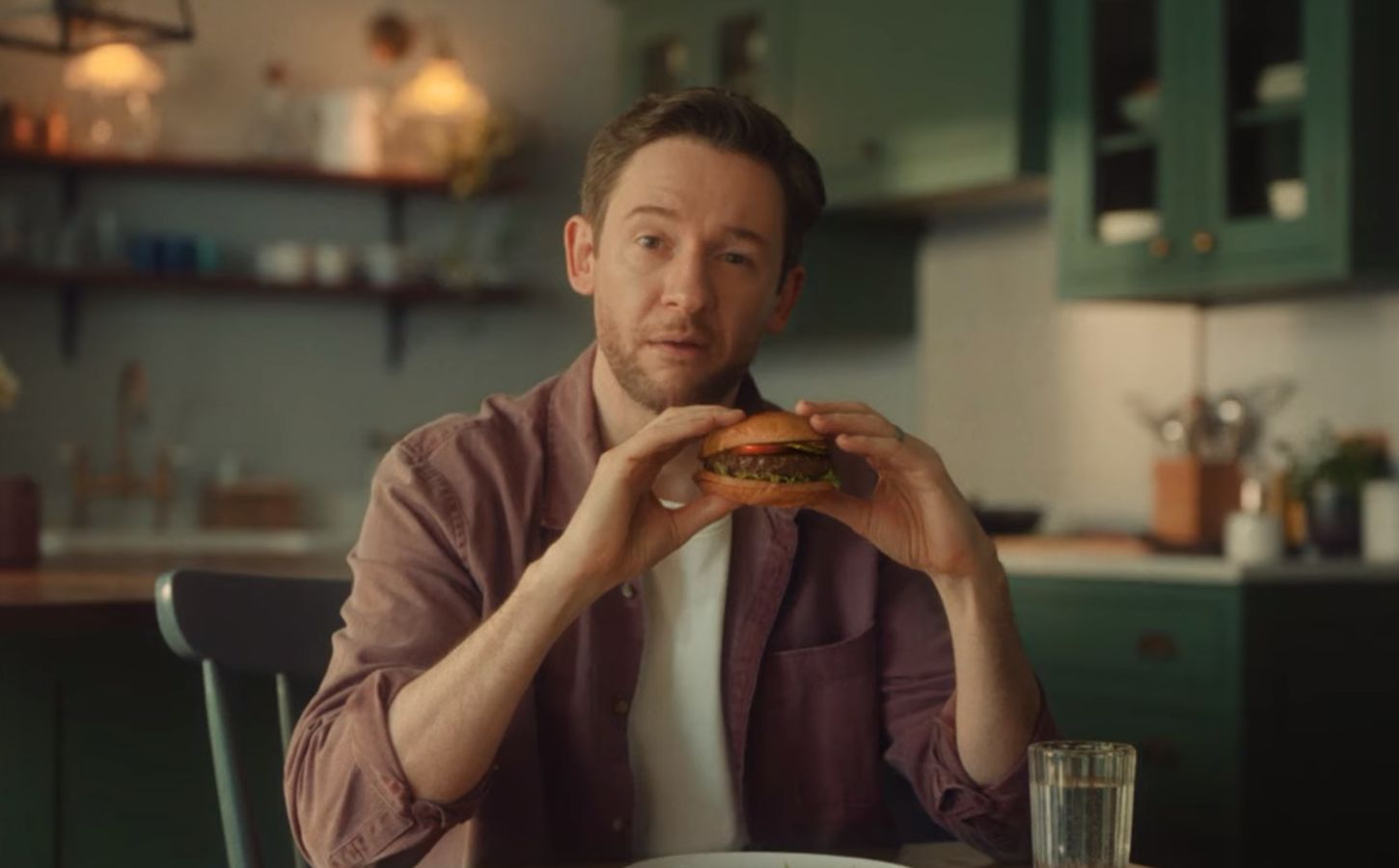 Screengrab from the new Beyond Meat advertisement shows someone eating a plant-based burger in a kitchen