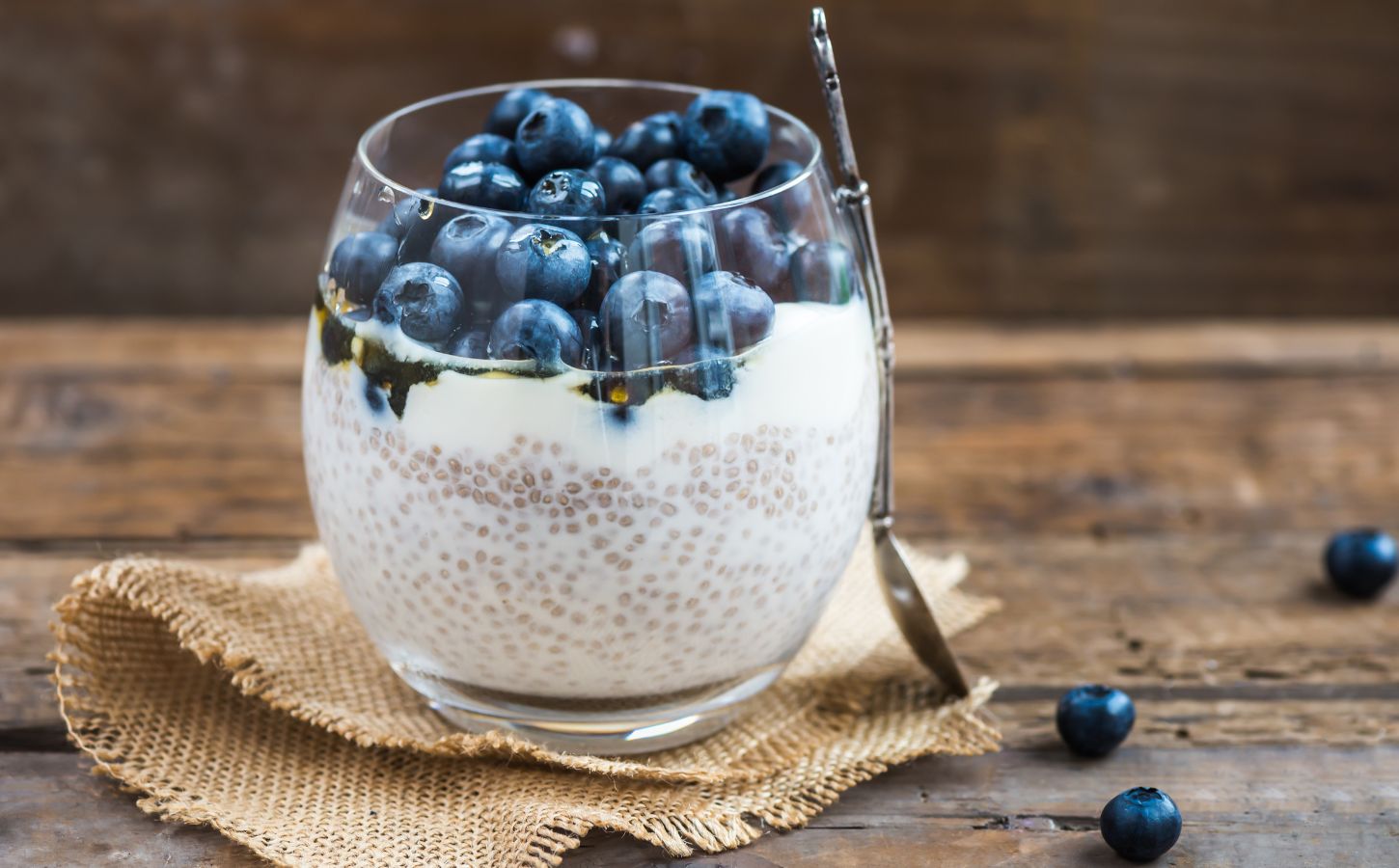 Picture shows a glass cup full of blueberry and chia seed pudding