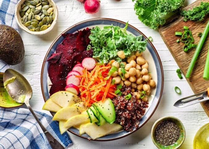Photo shows a colorful bowl of fresh fruit, vegetables, and salad