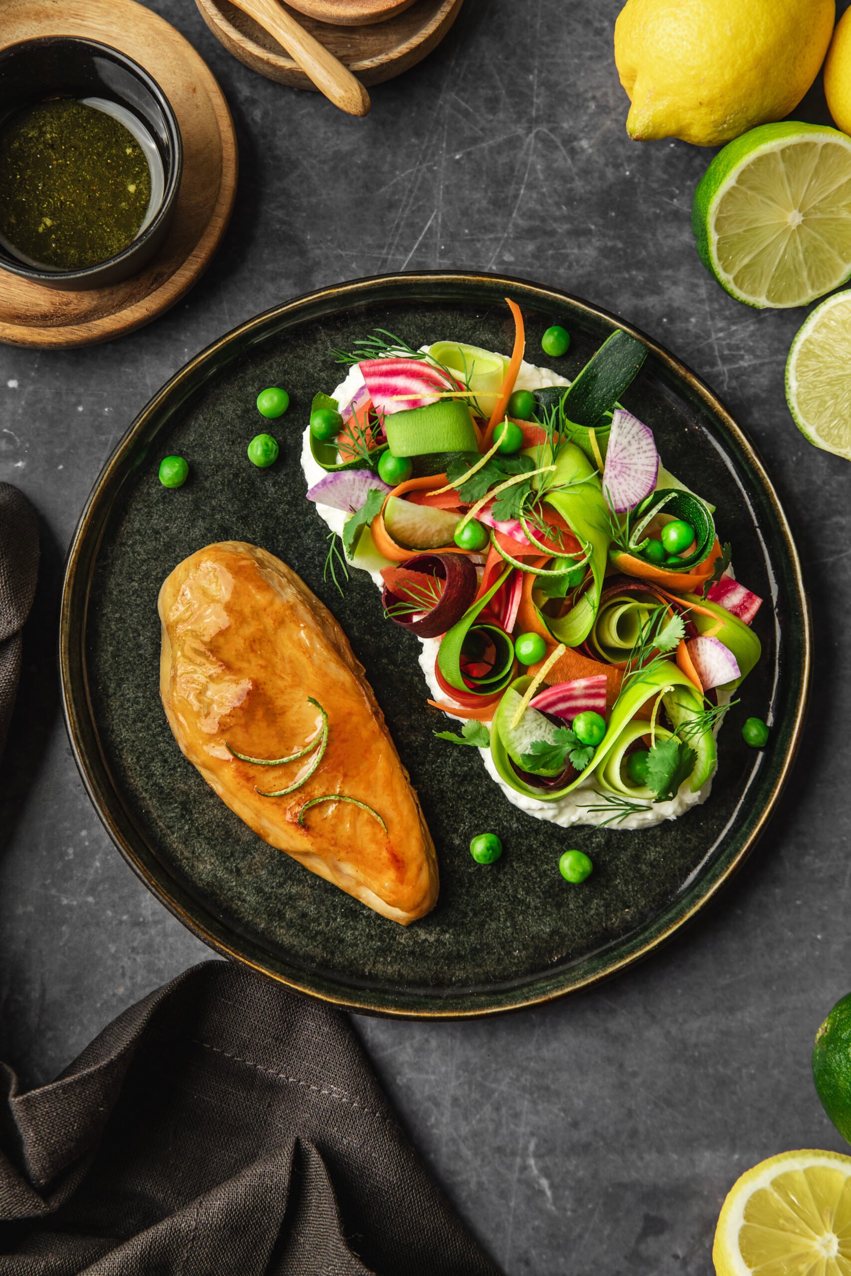 Photo shows a whole-cut plant-based chicken fillet made by Heura and Swap, dished up with fresh vegetables on a dark grey plate