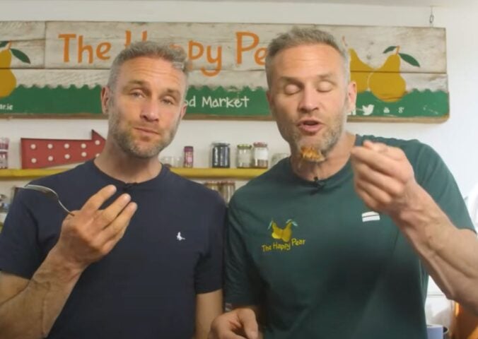 The Happy Pear twins David and Stephen Flynn eating high protein vegan lasagna in a still from a YouTube video on the recipe