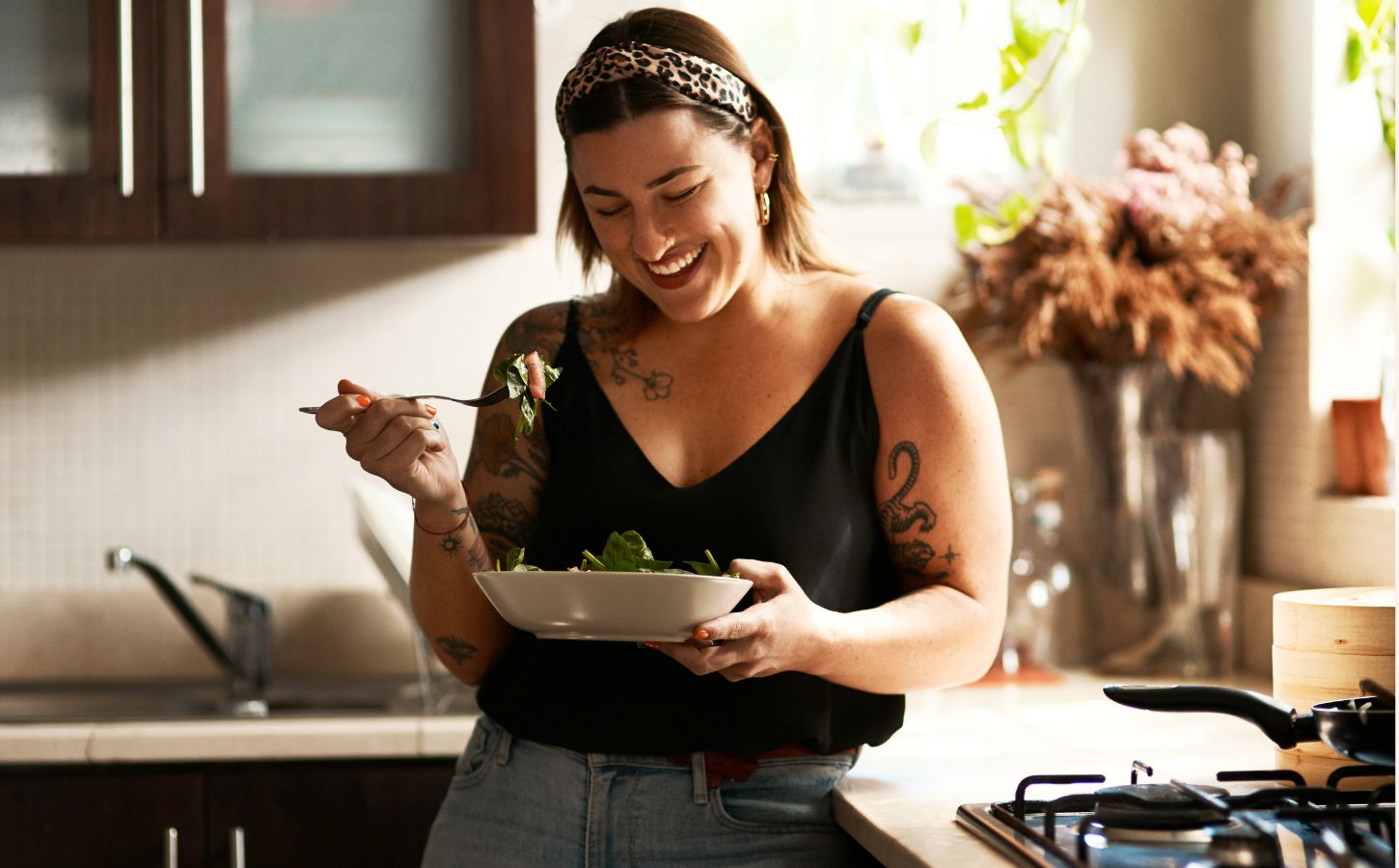 A woman eating a bowl of longevity superfood beans in a kitchen