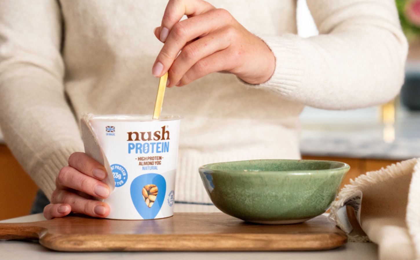 A person spooning a Nush high protein, soy-free yogurt