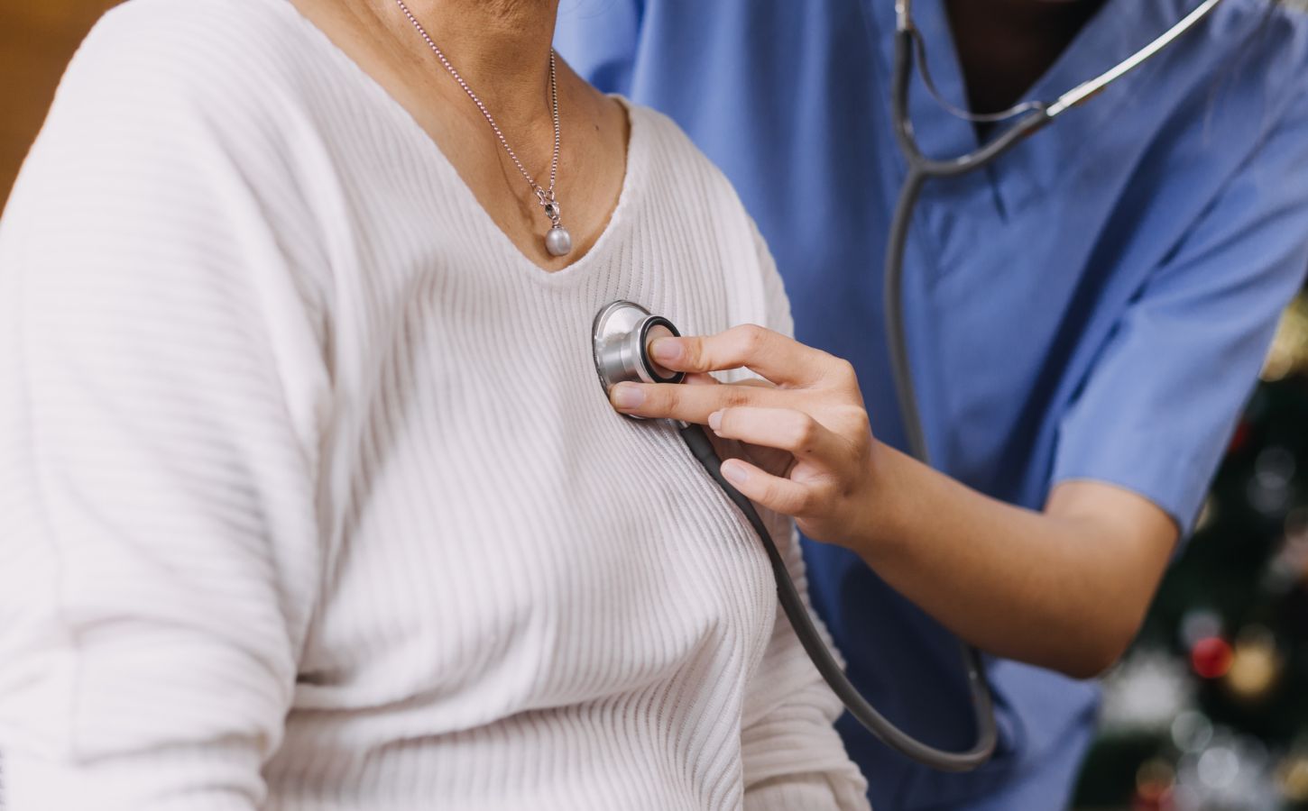 Photo shows a Dr or other healthcare professional using a stethoscope on a patient