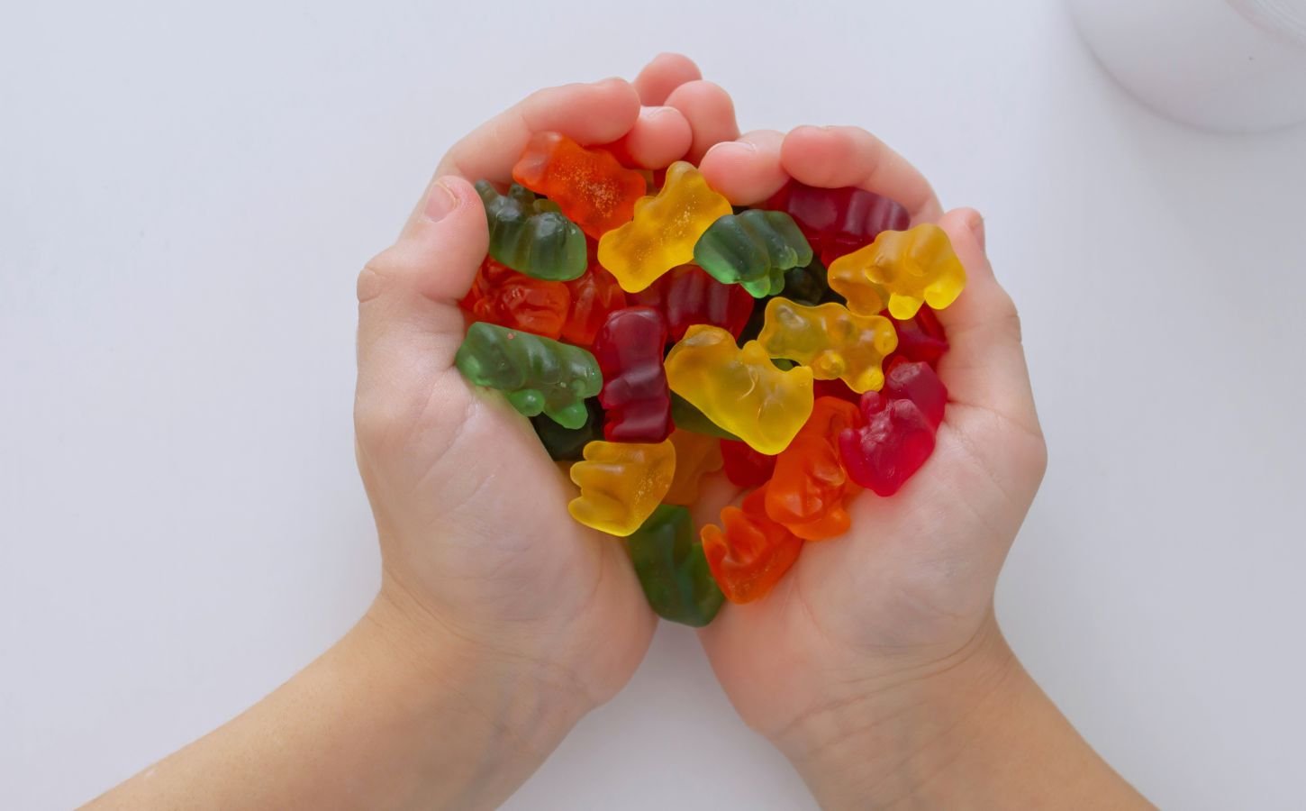 Photo shows a child's hands as he cups jelly beans in the shape of a heart
