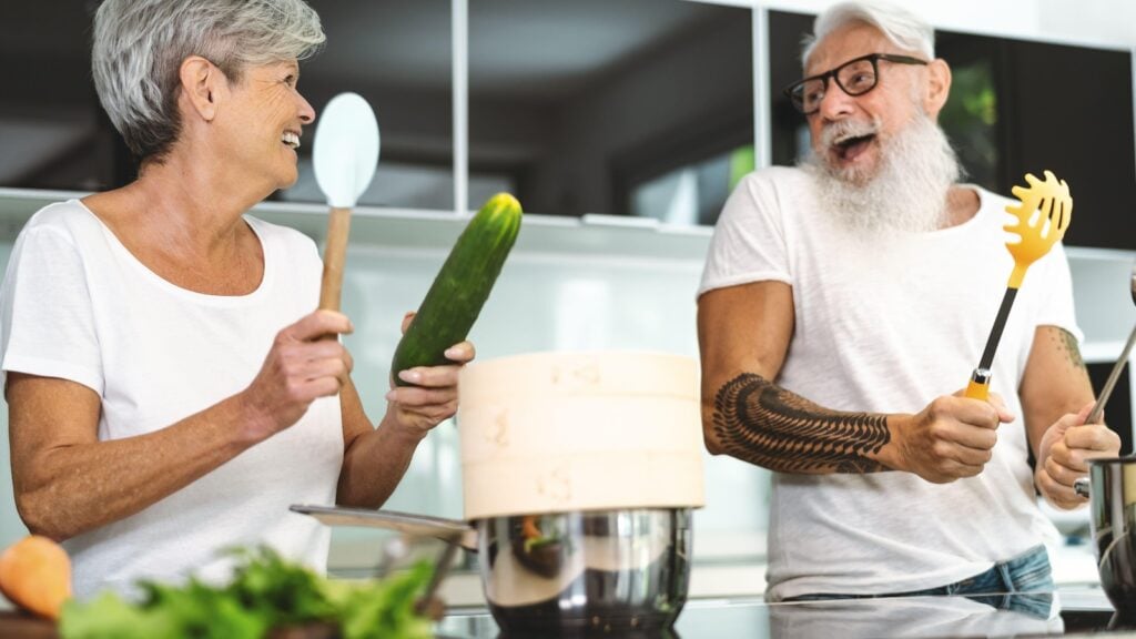 happy senior couple having fun cooking together in the kitchen