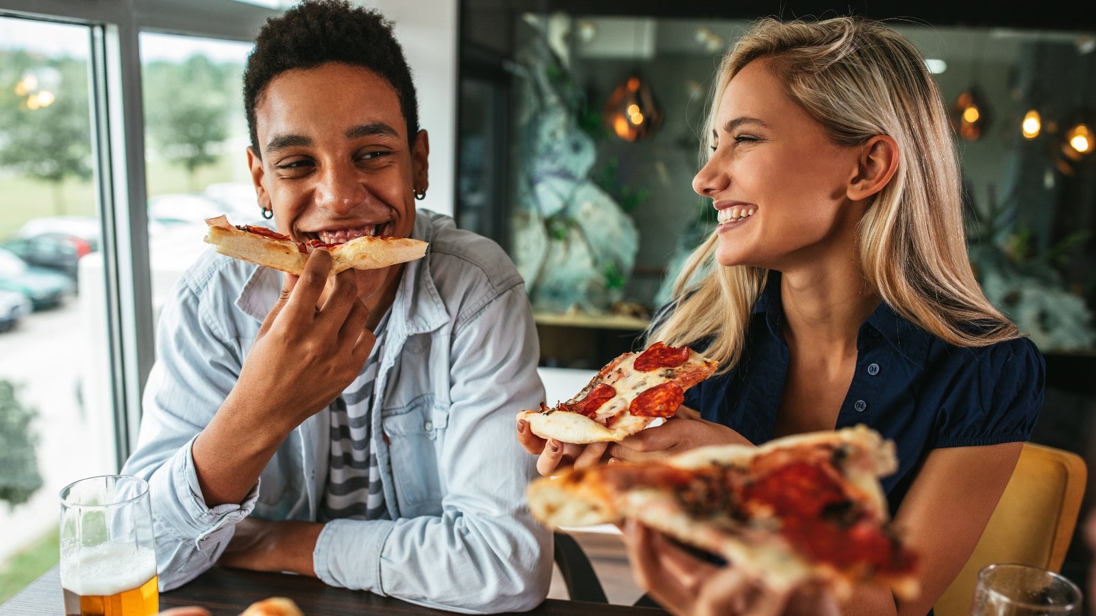 Two people eating pizza and smiling
