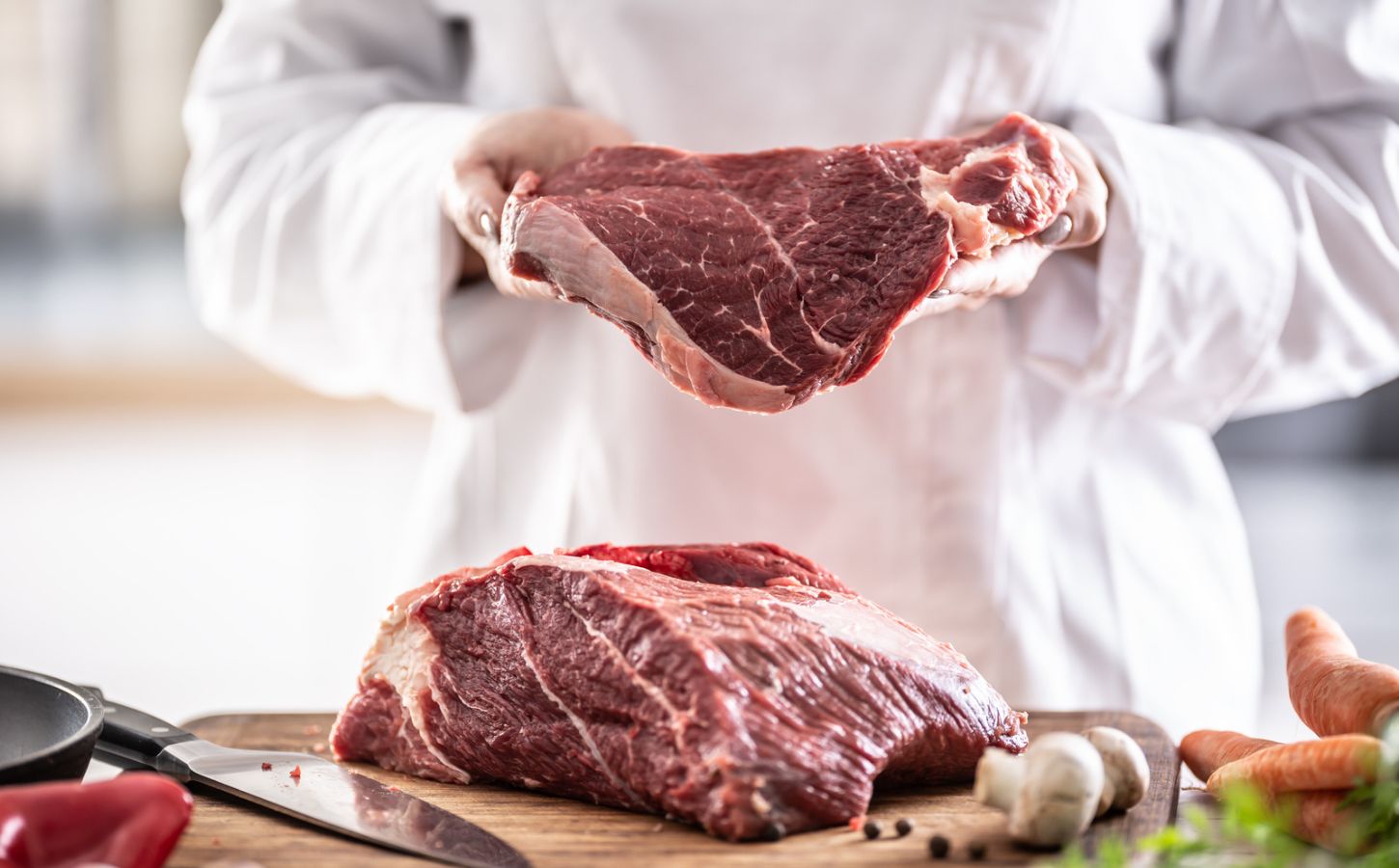Slabs of red meat being handled by a butcher