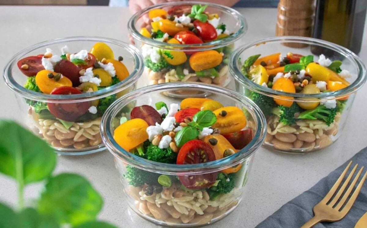 A vegan bean, orzo, pesto salad, all divided into separate containers for meal-prepping