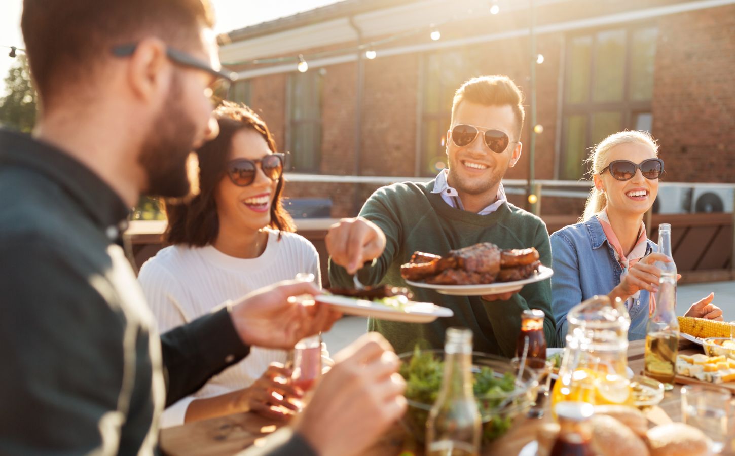 A group of friends sitting in the sun and eating meat