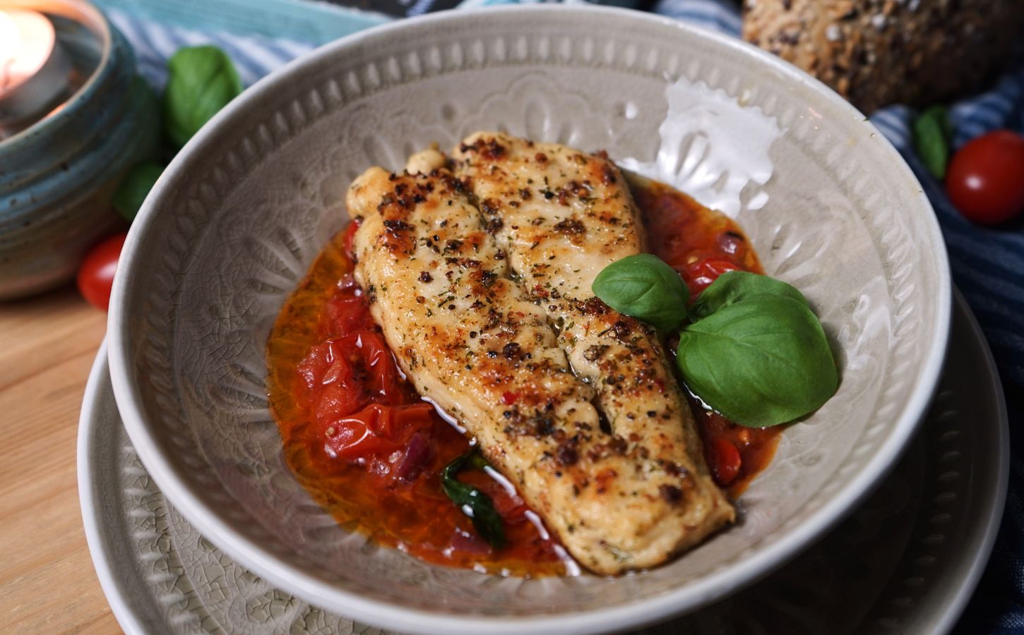 Photo shows two fillets of the latest Revo Foods product, vegan black cod, in a dish with a tomato-based sauce and green garnish
