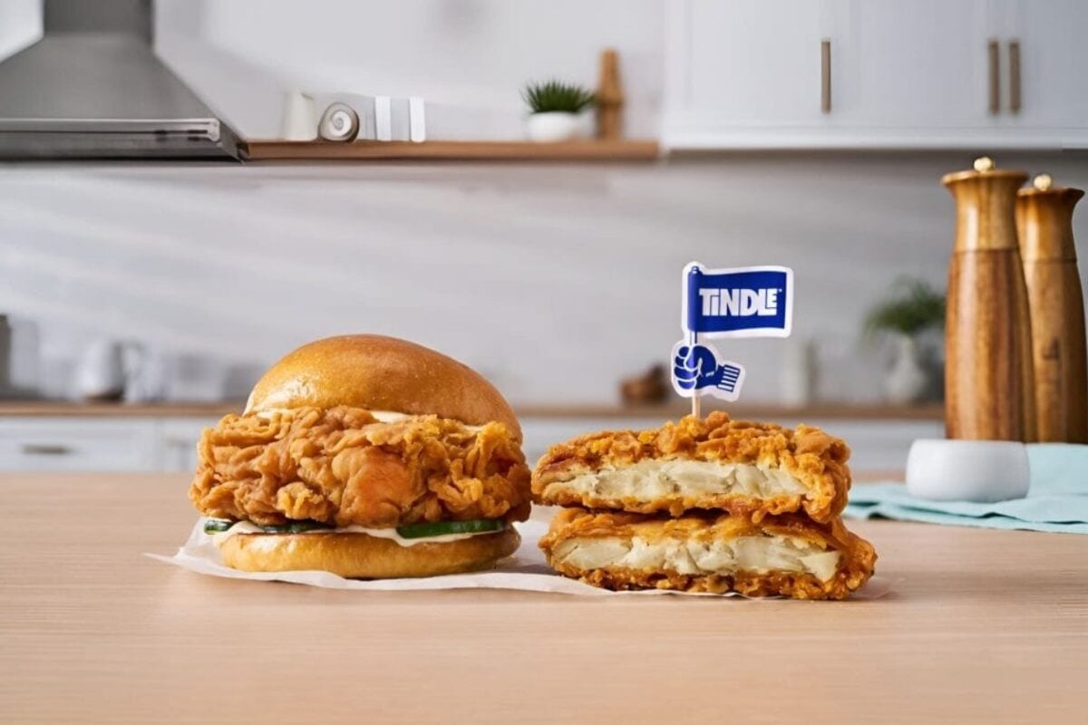 Photo shows a chicken burger next to a disassembled patty made with TiNDLE's plant-based chicken