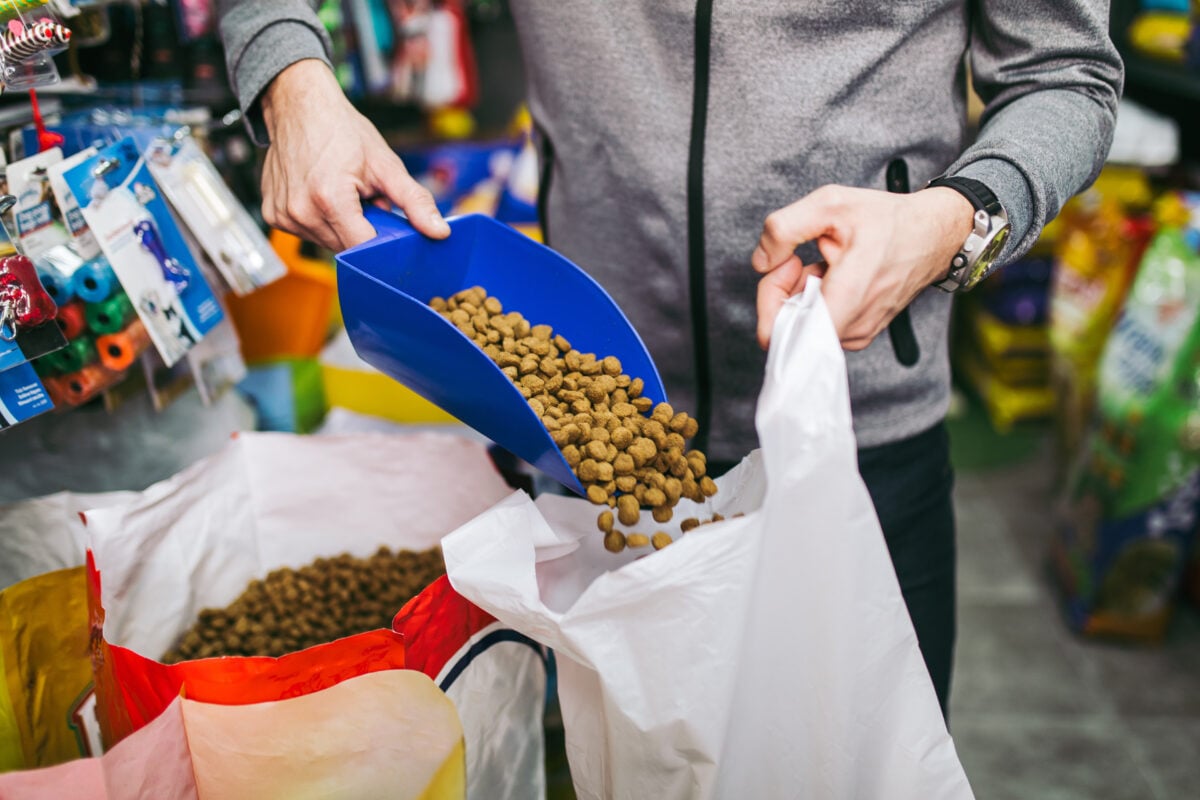 Photo shows someone scooping pet food into a plastic bag